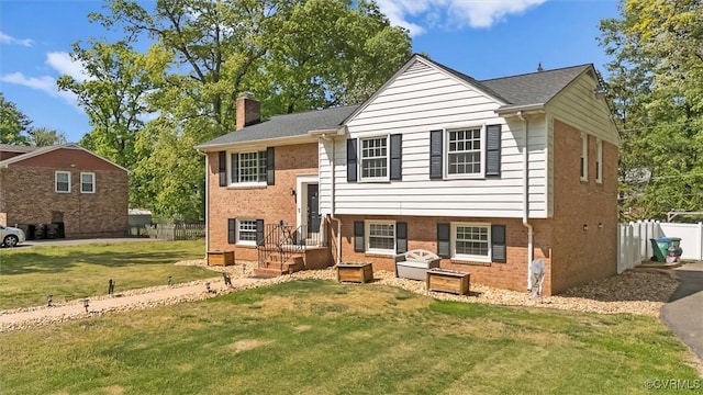 rear view of property featuring a lawn, fence, a chimney, and brick siding