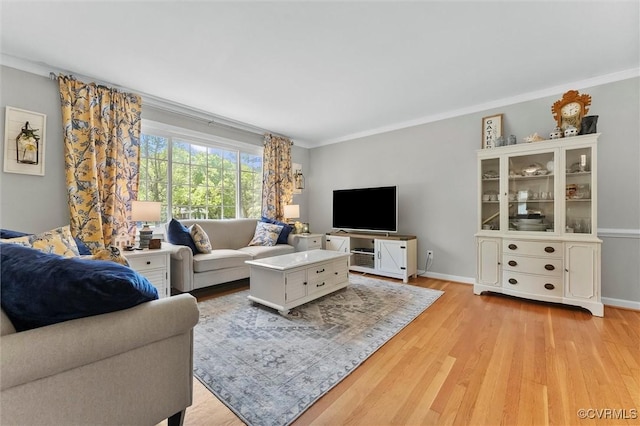 living area featuring baseboards, ornamental molding, and light wood-style floors