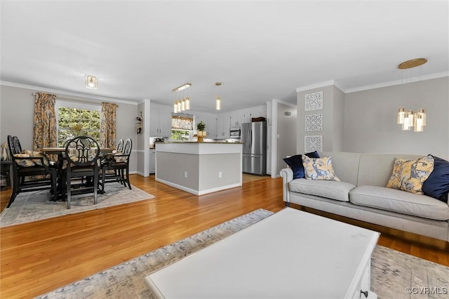 living room with a chandelier, light wood-type flooring, and ornamental molding