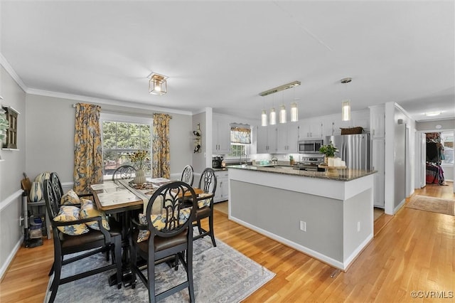dining room featuring ornamental molding, baseboards, and light wood-type flooring