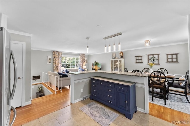 kitchen featuring light tile patterned flooring, freestanding refrigerator, blue cabinets, and open floor plan