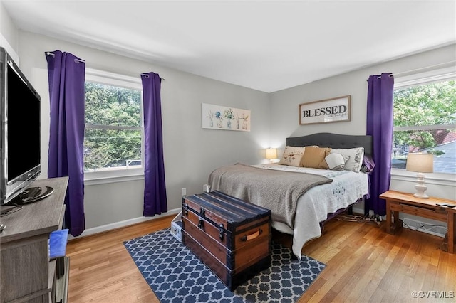 bedroom featuring multiple windows, light wood-style flooring, and baseboards