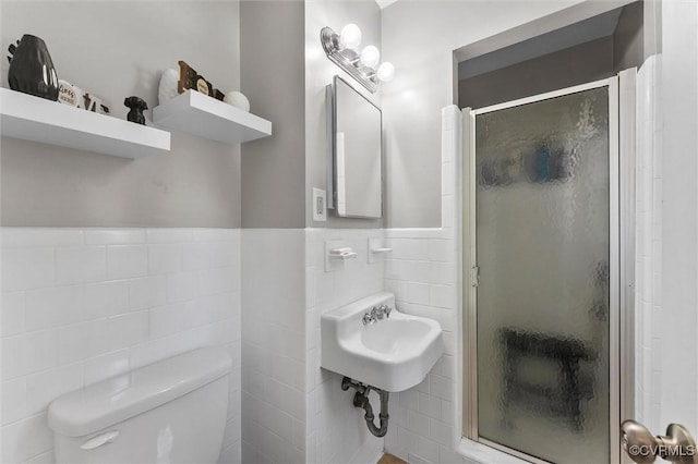 full bath featuring toilet, a stall shower, tile walls, and a wainscoted wall