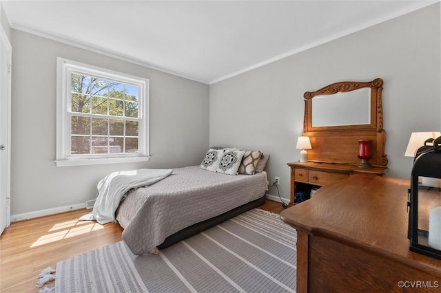 bedroom with wood finished floors, crown molding, and baseboards