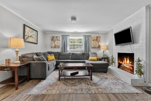 living area featuring ornamental molding, a brick fireplace, and wood finished floors