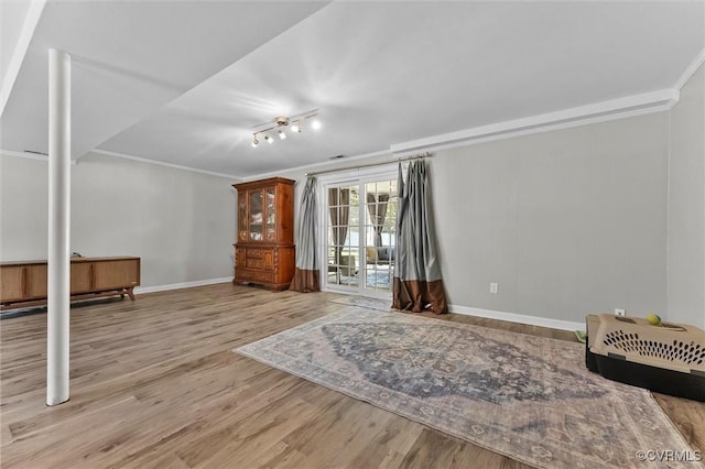 unfurnished living room featuring ornamental molding, wood finished floors, and baseboards