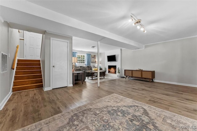 below grade area with wood finished floors, a warm lit fireplace, and baseboards
