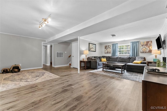 living area with track lighting, wood finished floors, stairway, baseboards, and visible vents