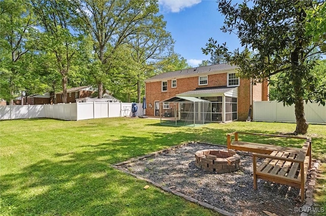 view of yard with a fenced backyard, an outdoor fire pit, and a sunroom