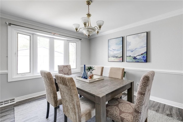 dining room with visible vents, wood finished floors, baseboards, an inviting chandelier, and ornamental molding