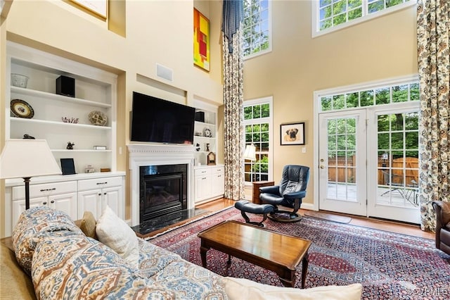9522 Nassington Ct, Henrico, VA 23229 - living area featuring healthy amount of natural light, built in features, a glass covered fireplace, a high ceiling, and wood finished floors
