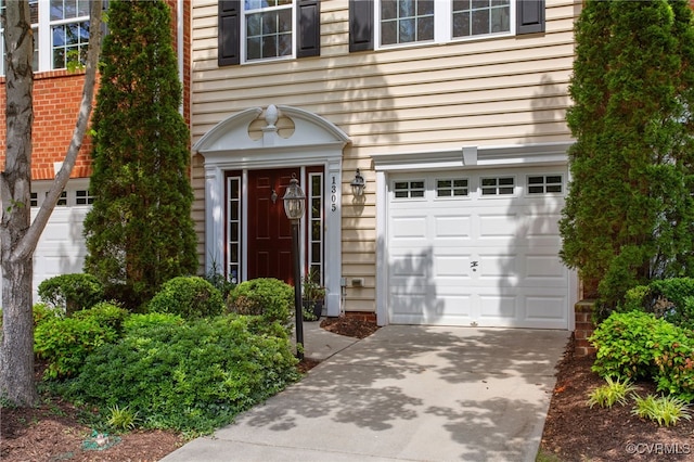property entrance featuring an attached garage and driveway