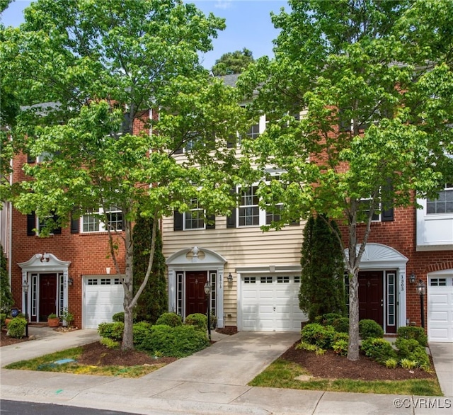 view of property featuring a garage, driveway, and brick siding