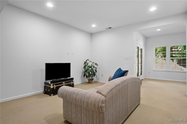 living area with recessed lighting, visible vents, and light carpet
