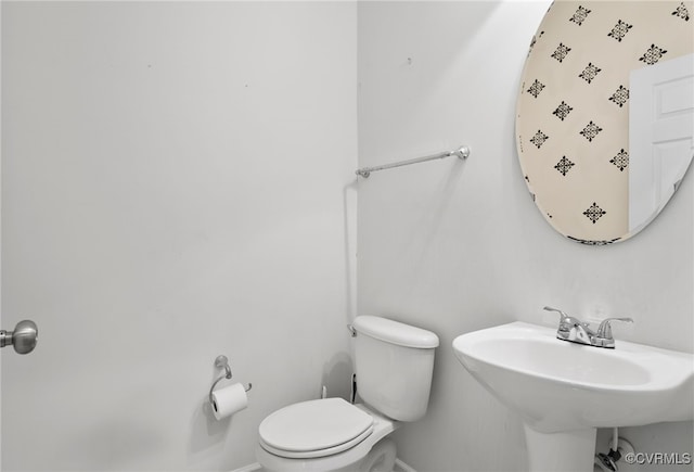 half bathroom featuring baseboards, a sink, and toilet