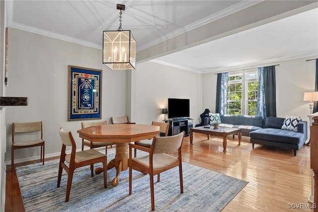 dining room with an inviting chandelier, ornamental molding, baseboards, and light wood-type flooring