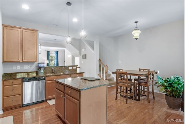 kitchen featuring a sink, dishwasher, dark stone countertops, light wood-type flooring, and a kitchen island