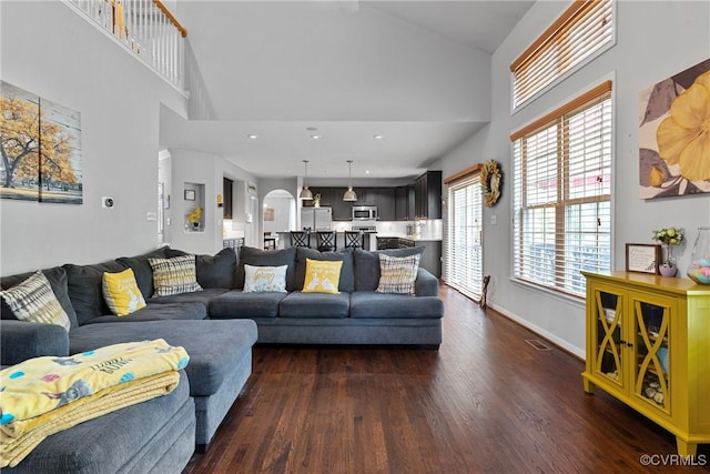 living room featuring visible vents, high vaulted ceiling, baseboards, and dark wood finished floors