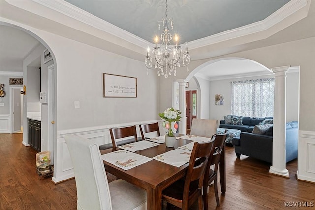 dining space with dark wood-style flooring, ornamental molding, wainscoting, and arched walkways