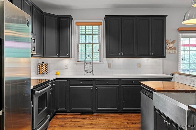 kitchen with dark cabinets, tasteful backsplash, stainless steel appliances, and dark wood-type flooring