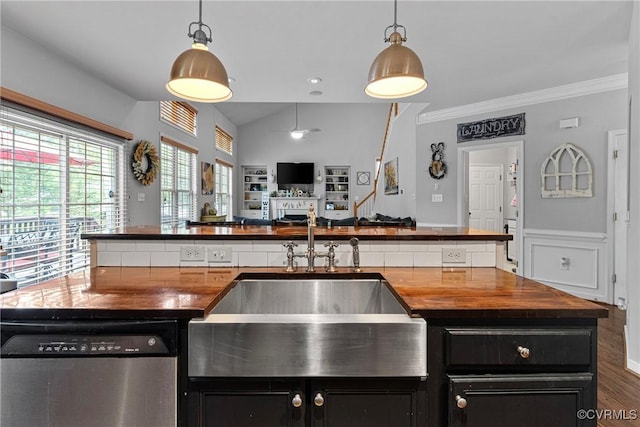 kitchen with a sink, stainless steel dishwasher, butcher block countertops, and dark cabinetry