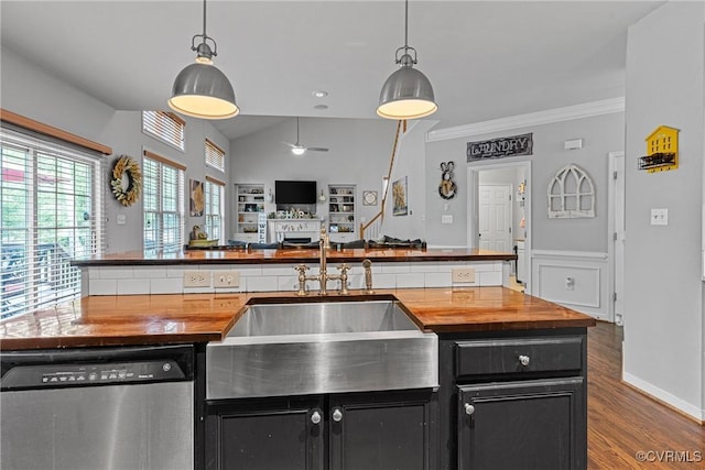 kitchen with stainless steel dishwasher, a sink, wood counters, and dark cabinetry