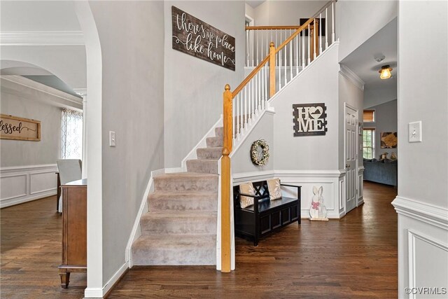stairway featuring ornamental molding, arched walkways, and wood finished floors