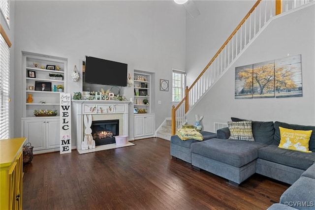 living area with wood finished floors, a premium fireplace, stairs, and a high ceiling
