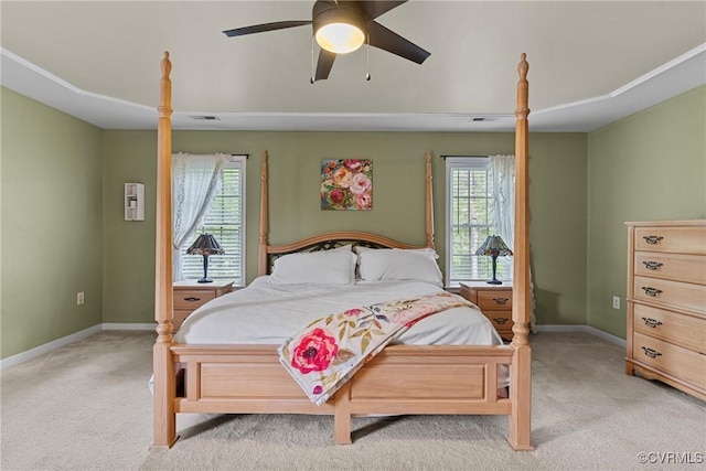 bedroom featuring baseboards, a ceiling fan, light carpet, and multiple windows