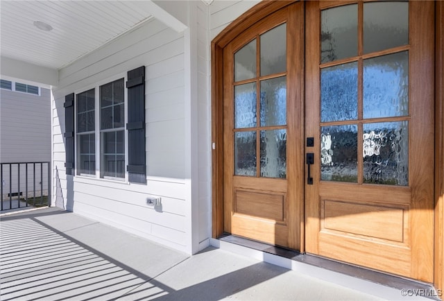 view of exterior entry featuring covered porch and french doors