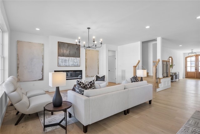 living room featuring light wood finished floors, recessed lighting, an inviting chandelier, stairway, and baseboards