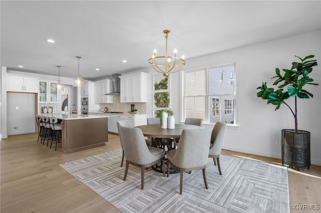 dining space with a chandelier, recessed lighting, light wood finished floors, and baseboards