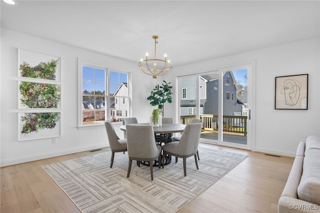 dining area with visible vents, baseboards, a chandelier, and light wood-style floors