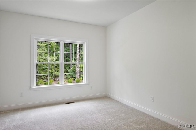empty room featuring carpet, visible vents, and baseboards