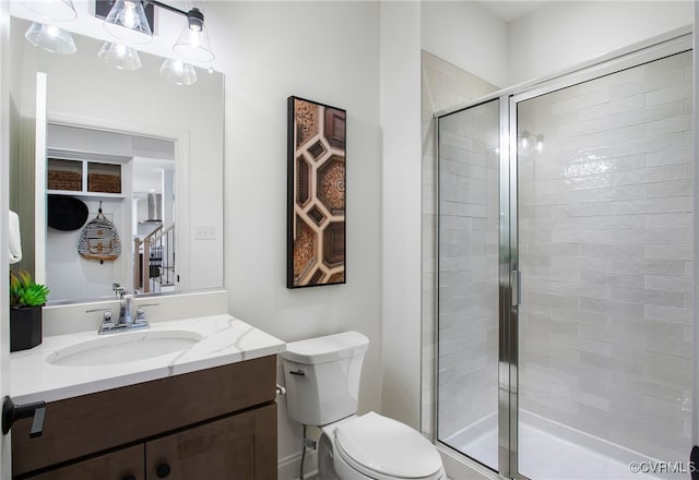 bathroom featuring toilet, a stall shower, and vanity
