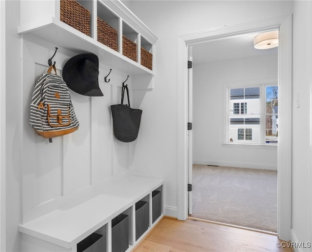 mudroom with light wood-style floors, light carpet, and baseboards
