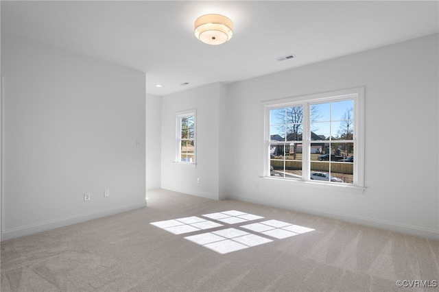 carpeted spare room featuring baseboards and visible vents