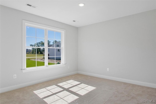 unfurnished room featuring light colored carpet, visible vents, a wealth of natural light, and baseboards
