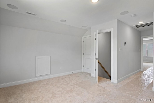 unfurnished room featuring baseboards, visible vents, light carpet, and lofted ceiling