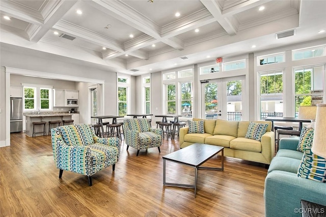 living area featuring crown molding, coffered ceiling, recessed lighting, and wood finished floors