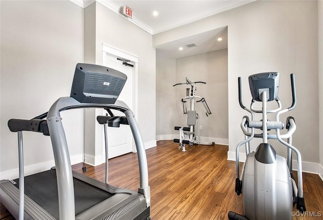exercise room with visible vents, wood finished floors, ornamental molding, and baseboards