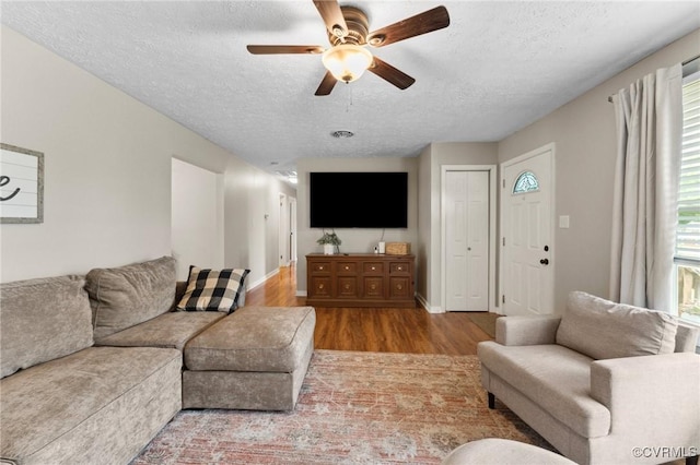 living room with baseboards, wood finished floors, ceiling fan, and a textured ceiling