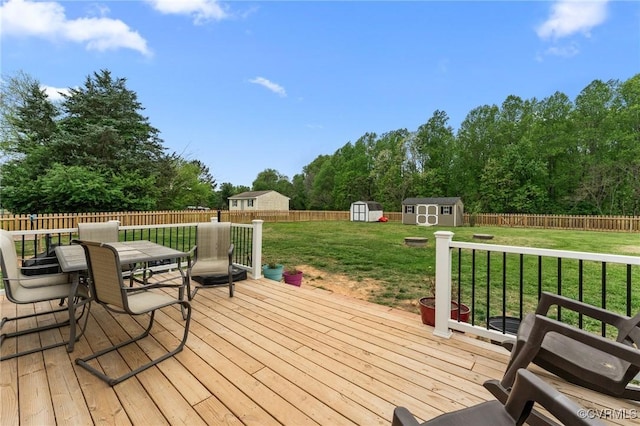 wooden terrace with a storage shed, a yard, an outbuilding, and a fenced backyard