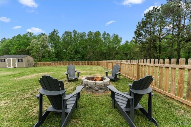 view of yard with a fire pit, an outbuilding, a storage unit, and a fenced backyard