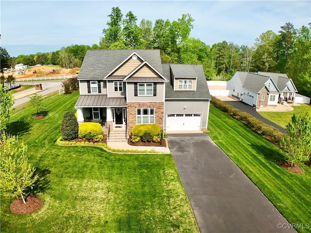 view of front of home with a standing seam roof, a front yard, driveway, and a porch