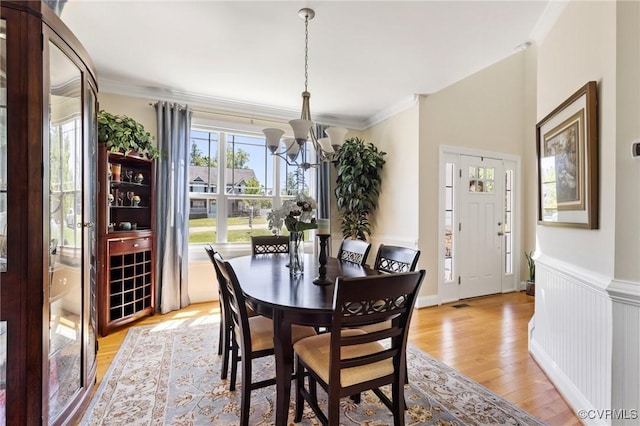 dining room with crown molding, light wood finished floors, and a chandelier