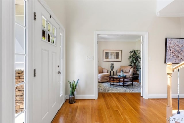 entrance foyer featuring baseboards, ornamental molding, and light wood-type flooring