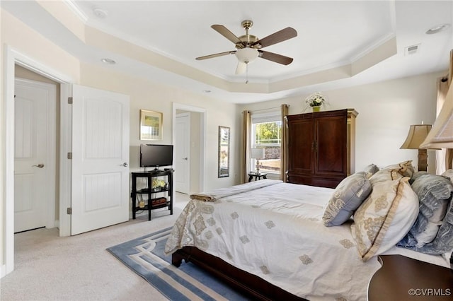 bedroom featuring ornamental molding, light carpet, a tray ceiling, and visible vents