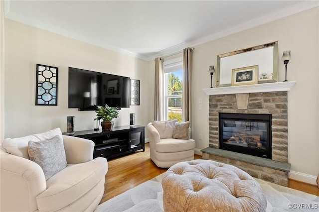 living room featuring a glass covered fireplace, baseboards, ornamental molding, and wood finished floors