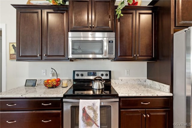 kitchen featuring dark brown cabinetry, light stone countertops, and stainless steel appliances